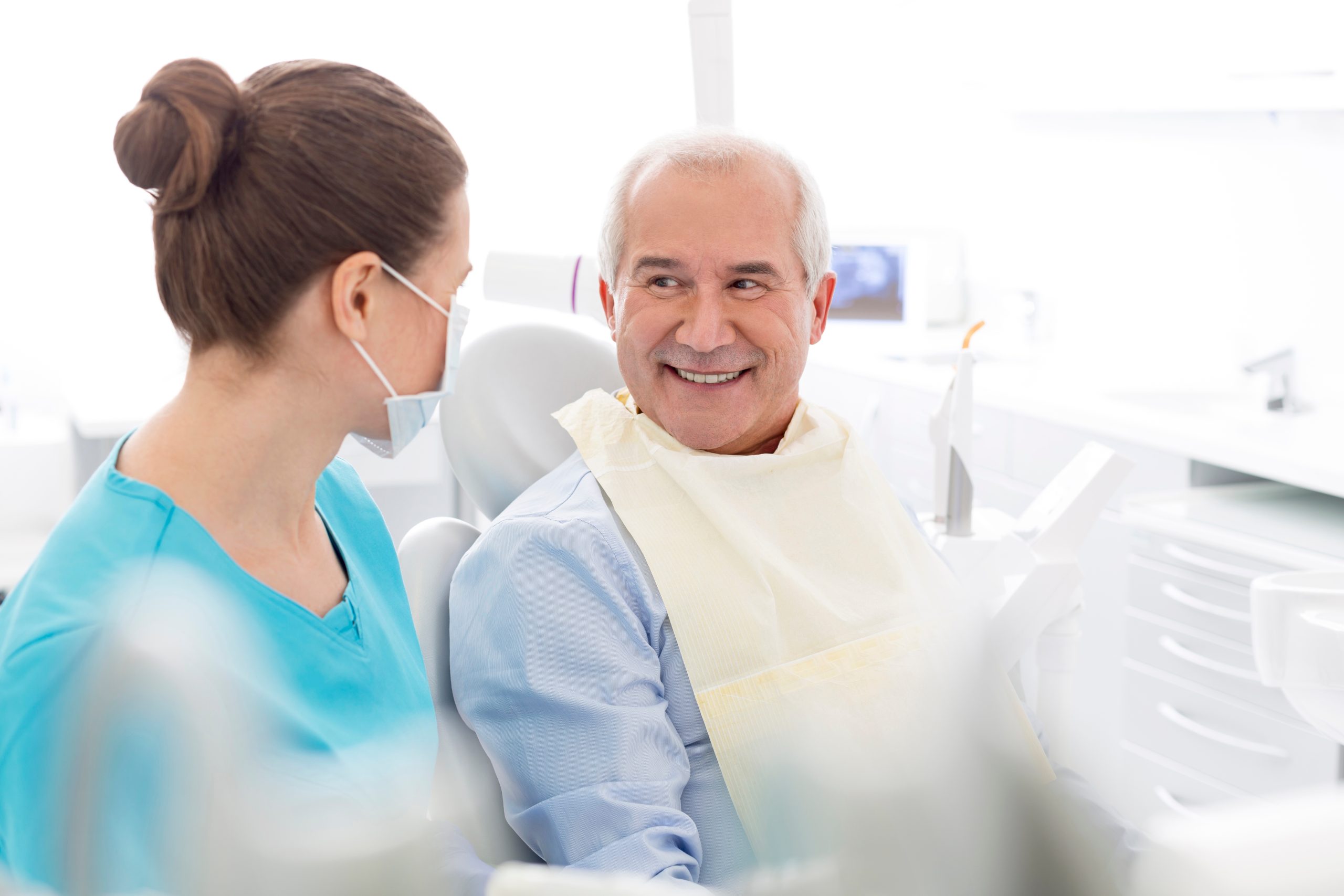 Female dentist talking to smiling senior patient at dental clinic