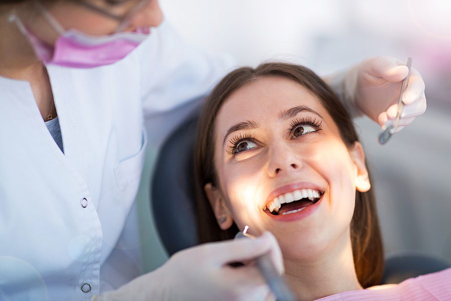 Young female patient smiling up at dentist with a bright, white smile.