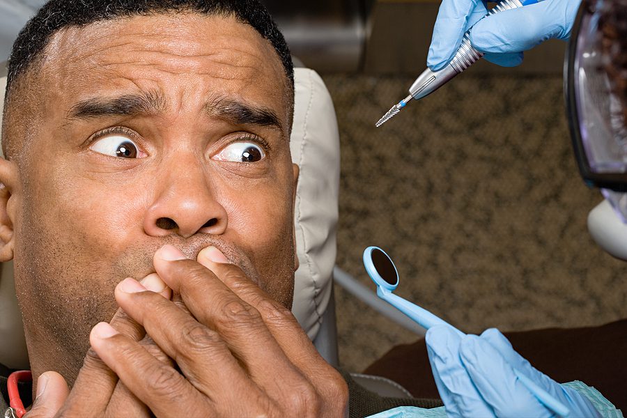 Man covering mouth while looking anxious about seeing the dentist. 