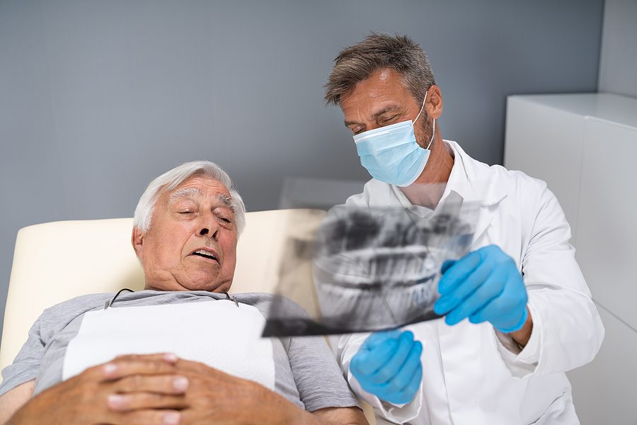 Older male patient looking at dental x-ray results with the dentist. 