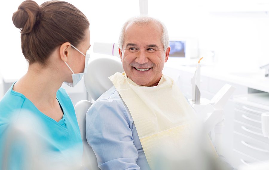 Older male patient speaking to a female dentist about his dental treatement options.